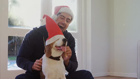 Smiling young man putting santa cap on his pet dog 4K 4k