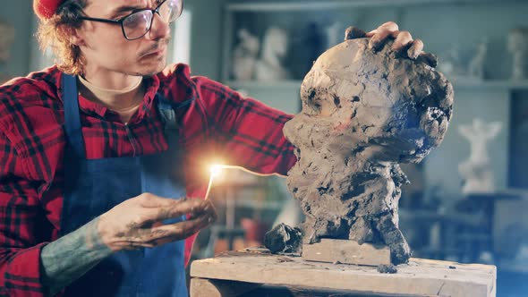 Male Sculptor is Working on a Head Molded Out of Clay