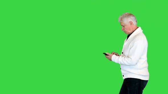 Modern Old Man Pensioner Walking and Texting on the Phone on a Green Screen Chroma Key