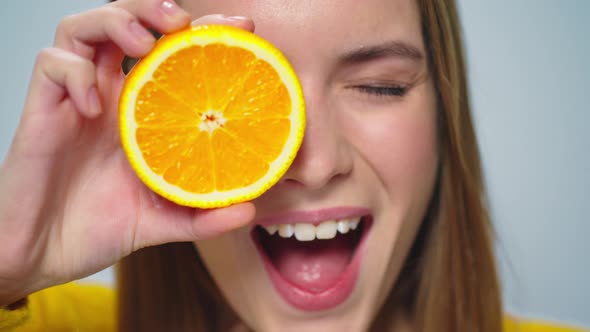Closeup Young Pretty Woman Making Faces with Two Orange Slices Indoors