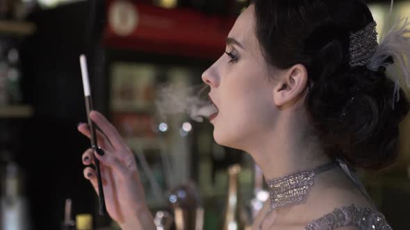 Portrait of a Young Attractive Woman in a 1920s Style Smoke Cigarette at the Bar