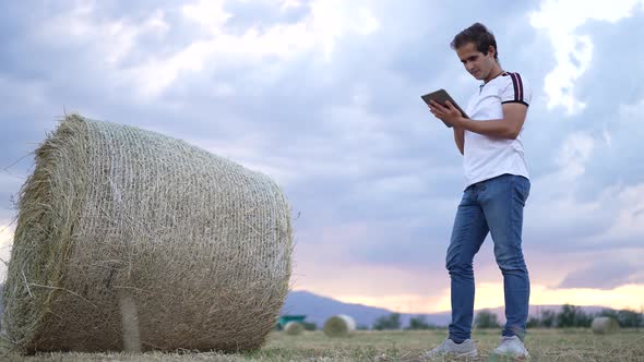 An agricultural engineer examines bales of hay.