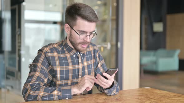 Young Designer Getting Success on Smartphone in Office