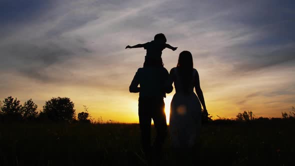 Adult Parents with Little Son Walking at Sunset