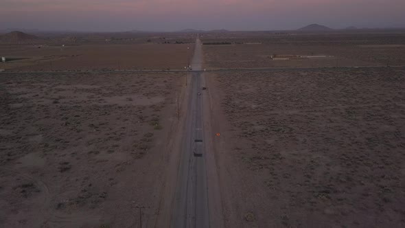 AERIAL: Flight Over Lonely Abandoned Desert Road with Red Car Driving in the Distance 