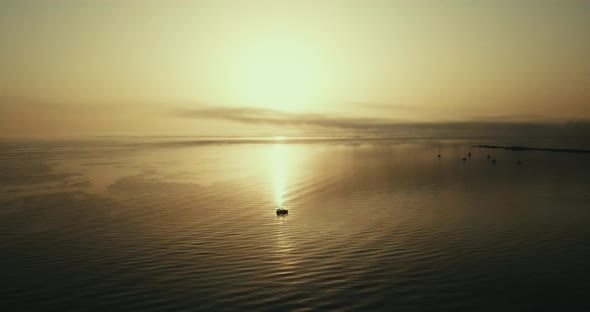 Ocean golden sunset view from aerial drone flight - little sail boat