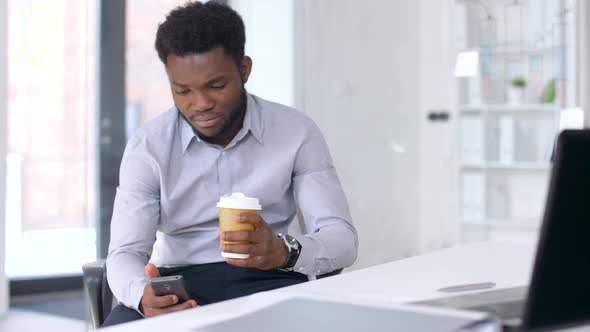 Businessman with Smartphone and Coffee at Office 
