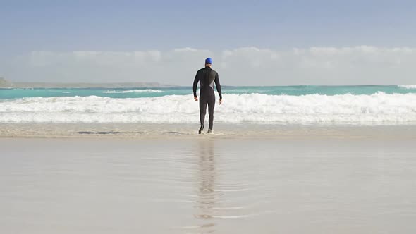 Rear view of male surfer walking in the beach 