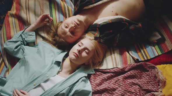 Young Loving Couple Lying on Bed and Looking at Camera