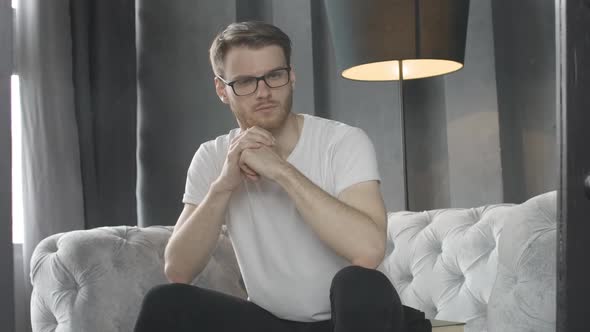 Portrait of Brunette Man Taking Off Eyeglasses and Looking at Camera with Serious Facial Expression