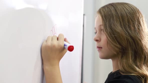 A Little Teenage Girl Goes to School Draws with a Marker on the Blackboard