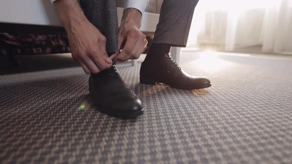 Hands of Man Groom Adjusting Wearing Putting His Wedding Shoes in Hotel Room Near Window