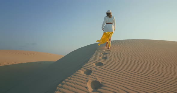 Young Woman Making Footprintings on Sand in Desert