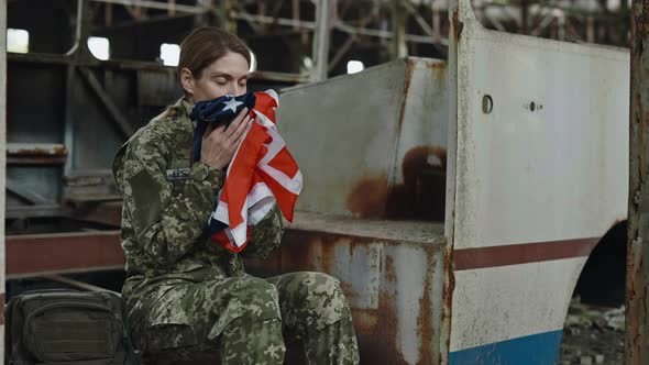 Female Soldier Holding American Flag on Ruined Plant