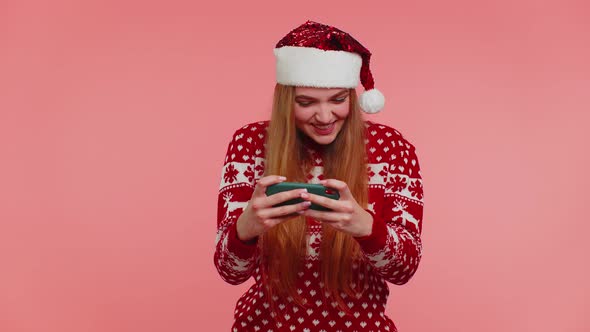 Worried Girl in Christmas Sweater Hat Enthusiastically Playing Racing Video Games on Mobile Phone