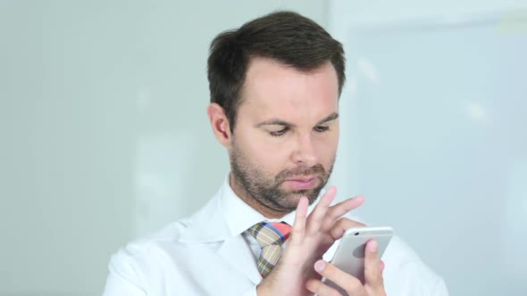 Doctor Browsing Online on Phone in Hospital Redhead