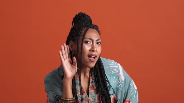 A confused shocked african american woman posing with hand over ear