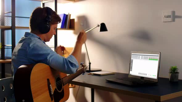 Man Playing Guitar and Recording Music at Home