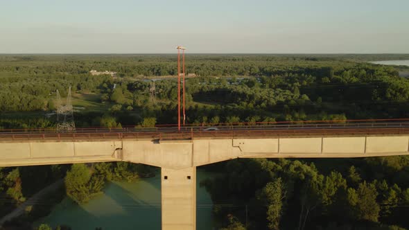 Dolly right flying alongside road and railway complex cable-stayed bridge with large green field, fo