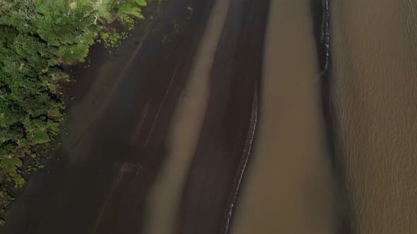 Aerial upward tilt of sandbanks and woodlands by Rio de la Plata coast