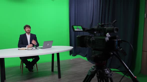 Portrait of an News Anchor Man Reporter Looks Into the Camera and Talks Backstage of Studio TV News