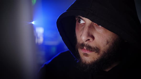 Male Criminal Hacker Working on a Computer in a Dark Office Room