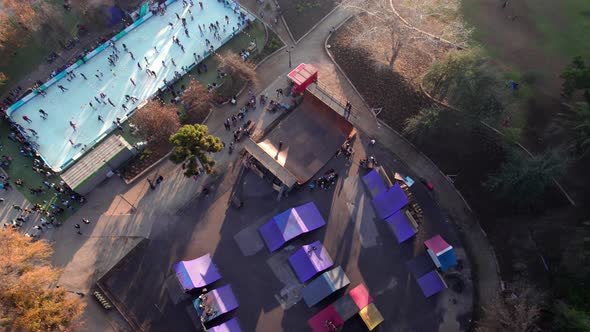 Aerial orbit of a skate park ramp with people skating on it, Parque Araucano, Santiago, Chile.