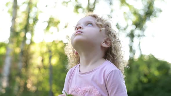 Portrait of a little beautiful curly-haired girl who looks into the sky