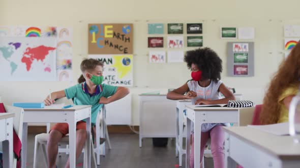 Two boys wearing face masks greeting each other by touching elbows at school