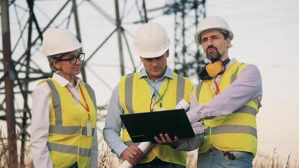 Men and a Woman Discuss Work Near Power Grids.