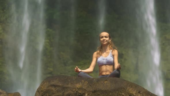 Girl Does Breathing Exercise Against Waterfall