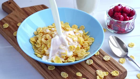 Pouring Milk Into Blue Bowl Full of Crunchy Cornflakes Cereal in Slow Motion