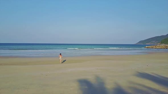 Backside View Flycam Shows Girl Running Along Ocean Beach