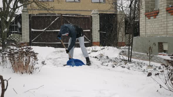 Man is shoveling snow in backyard in snow storm