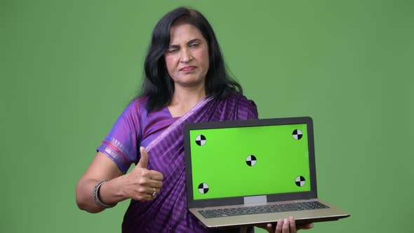 Mature Beautiful Indian Woman Showing Laptop and Giving Thumbs Up