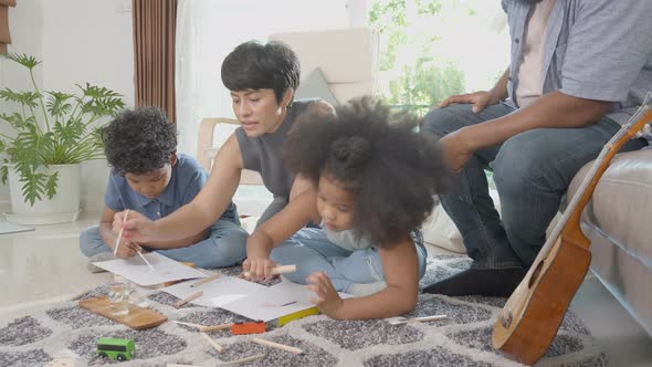 Happiness family with father and mother looking children drawing with colorful pencils.