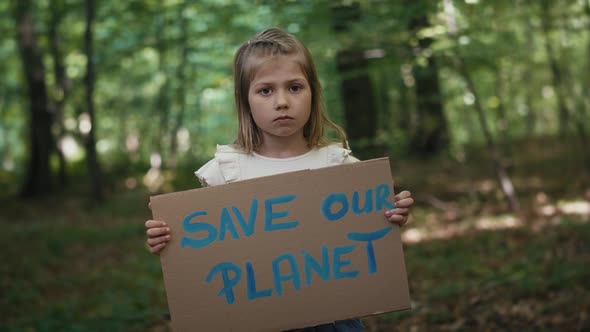 Portrait of little girl holding poster in the forest. Shot with RED helium camera in 4K.