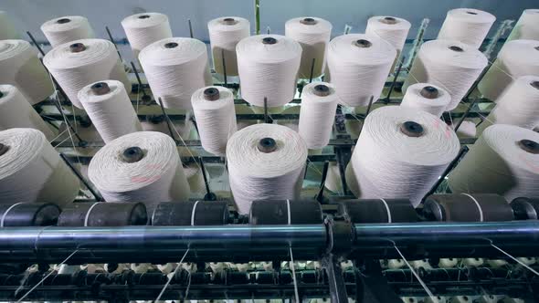 Many Spools with Fiber Spinning on a Factory Machine in a Facility. Textile Factory Equipment in