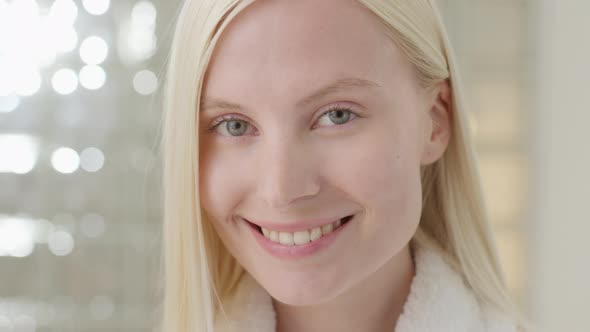 Young Caucasian Woman With Long Blond Hair Wearing a Bath Towel Looking at Camera in a Bright