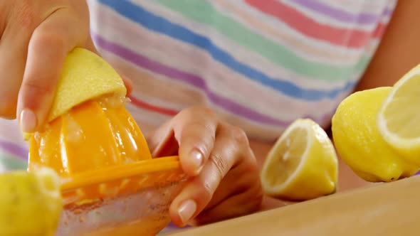 Woman preparing lime juice from juicer against violet background