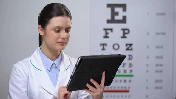 Lady Optometrist Checking Results in Tablet and Smiling to Camera, Technologies
