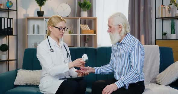 Doctor Checking Temperature on Old Man's Wrist Using Digital Thermometer when Visiting Him at home