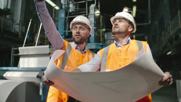 Architects Looking at Layout Plan of Factory