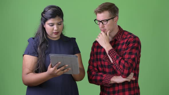 Young Multi-ethnic Business Couple Together Against Green Background