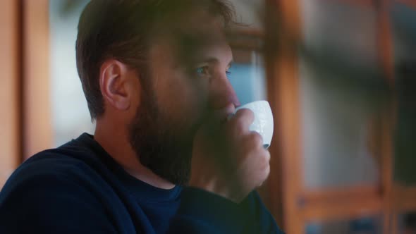 Relaxed Caucasian Man with Beard Drinks Coffee in a Cafe