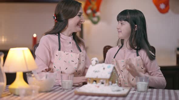 Satisfied Mother and Daughter Gesturing Highfive Hugging at Table with Ginger House