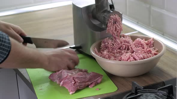 Mans Hands Cut Raw Meat with the Knife in the Kitchen