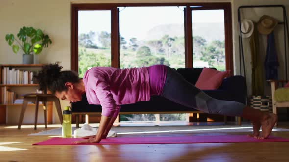 Mixed race woman practicing yoga on yoga mat at home