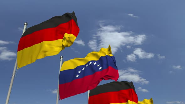 Waving Flags of Venezuela and Germany on Sky Background alt
