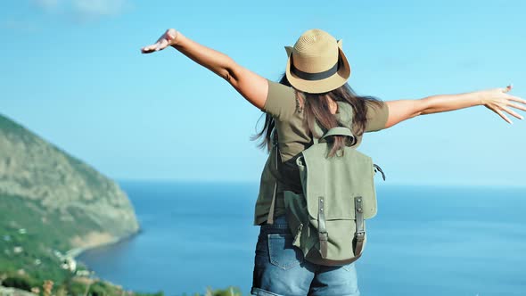 Active Backpacker Woman Traveler in Hat and Sunglasses Enjoying Amazing Seascape Raising Hands